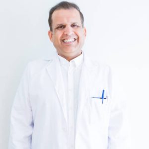 Middle age doctor man wearing medical coat over white background with a happy and cool smile on face. Lucky person.